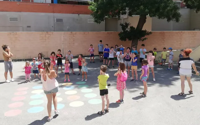 Beneficios de las actividades extraescolares en la infancia. Grupo de niños realizando extraescolar en el patio de colegio.